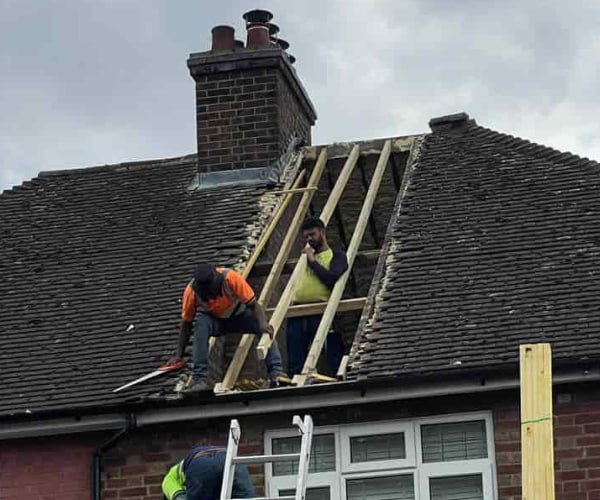 This is a photo of a roof repair being carried out. A section of the roof has been stripped and two roofers are replacing the rafters. Works being carried out by WS Roofing South Elmsall