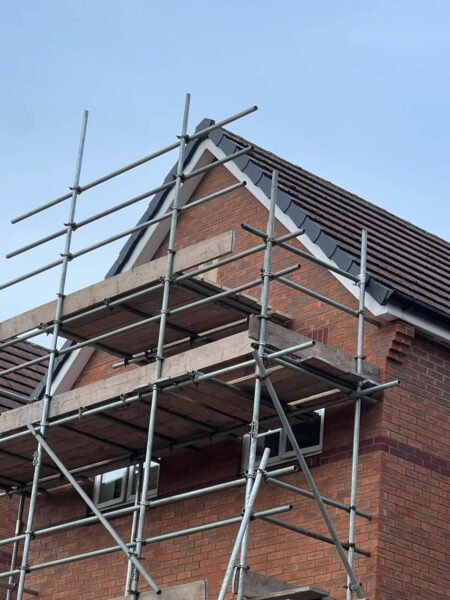 This is a photo of a roof which has just been repaired. There is a scaffold located at the gable end for access onto the roof.